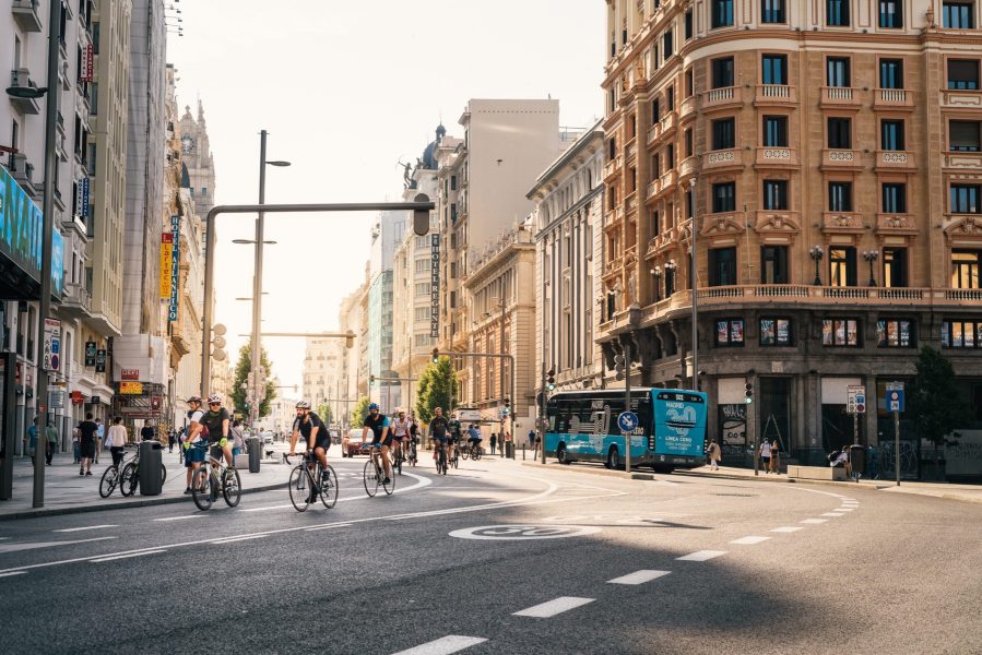 Una ciclista circula por un carril bici de Madrid seguida de un autobús municipal, dos opciones de transporte sostenible en la capital española